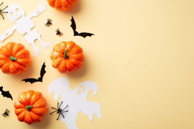 Halloween decorations concept. Top view photo of pumpkins spiders ghost skeleton and bats silhouettes on isolated beige background with empty space
