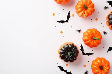 Halloween party decor concept. Top view photo of small pumpkins bat silhouettes spiders and confetti on isolated white background with empty space