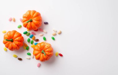 Halloween concept. Top view photo of orange pumpkins and candies on isolated white background with copyspace