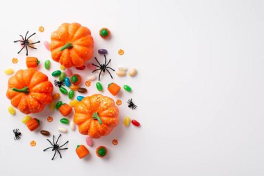 Halloween party concept. Top view photo of pumpkins spiders candies and confetti on isolated white background with empty space