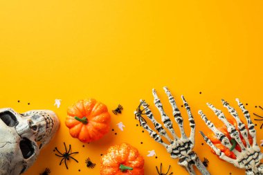 Halloween creepy decor concept. Top view photo of skull skeleton hands pumpkins spiders ghost silhouettes and confetti on isolated orange background with copyspace