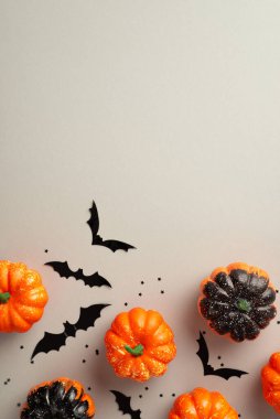Halloween concept. Top view vertical photo of pumpkins bat silhouettes and confetti on isolated grey background with empty space
