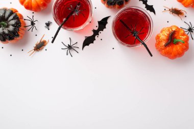 Halloween party concept. Top view photo of drink in glasses with floating spiders and straws pumpkins bat silhouettes spiders centipede and cockroaches on isolated white background with empty space