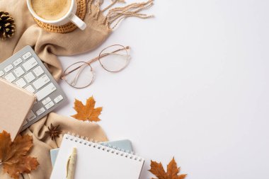 Autumn business concept. Top view photo of workspace keyboard notepads cup of coffee rattan serving mat stylish glasses pen yellow maple leaves pine cone anise and plaid on isolated white background