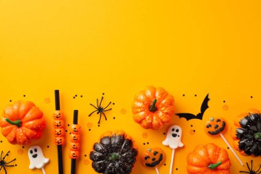 Halloween party decorations concept. Top view photo of pumpkins straws ghost shaped lollipops spiders bat silhouette and confetti on isolated orange background with empty space