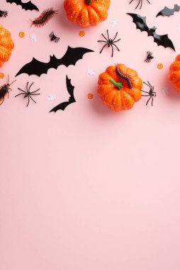Halloween concept. Top view vertical photo of bat silhouettes pumpkins insects spiders cockroach centipedes and confetti on isolated pastel pink background with copyspace