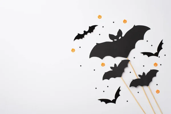 Halloween party decorations concept. Top view photo of bat silhouettes and confetti on isolated white background with empty space