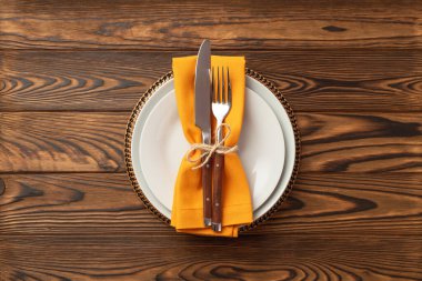 Thanksgiving day concept. Top view photo of table setting plate knife fork and napkin on isolated dark wooden table background