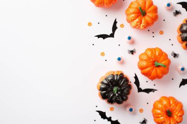 Halloween decorations concept. Top view photo of pumpkins spooky eyeballs bat silhouettes spiders and confetti on isolated white background with empty space