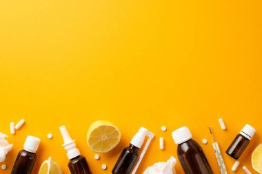 Illness concept. Top view photo of remedy spray and syrup brown bottles pills capsules thermometer crumpled napkins and cut lemon on isolated orange background with copyspace