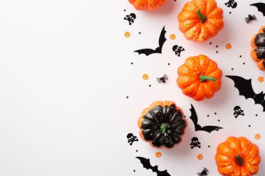 Top view photo of halloween decorations small pumpkins bats skull crossed bones silhouettes spiders and black confetti on isolated white background with blank space