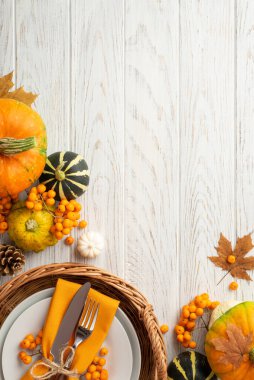 Şükran Günü konsepti. Üst görünüm dikey fotoğraf rattan sepet ile plaka bıçak çatal peçeteler pattypan kozalak akçaağaç akçaağaç Rowan 'dan kopyalanmış beyaz ahşap masa zemininde kopyalanmış