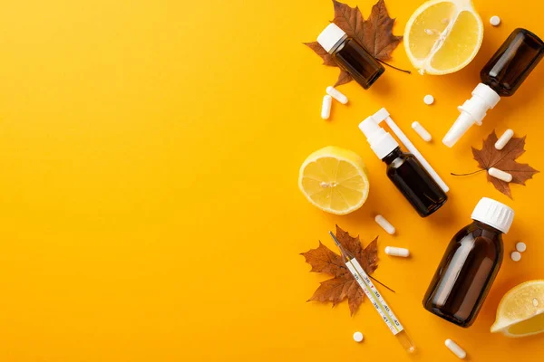 Seasonal diseases concept. Top view photo of spray and syrup transparent brown bottles pills capsules thermometer maple leaves and lemon halves on isolated orange background with empty space