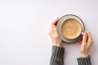Sonbahar ilham konsepti. Üstten bakıldığında, gri kazaklı bir kadının ellerinin fotografı. Elinde bir fincan köpüklü kahve, izole edilmiş beyaz arka planda, boş bir alanda.