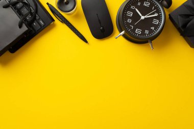 Kara Cuma indirim konsepti. Siyah hediye kutusu kağıdının üst görünümü alarm saati mum kalem bilgisayar faresi ve klavye boş arkaplan ile izole edilmiş sarı arkaplan