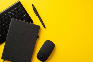 Ofis malzemelerinin en üstteki görüntüsü PC bilgisayar klavyesini not edin. Siyah renklerle izole edilmiş, parlak sarı arkaplan ve boş alan.
