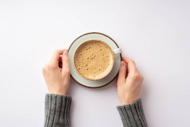 Sonbahar moda konsepti. Gri kazaklı, elinde bir fincan köpüklü kahveyle izole edilmiş beyaz arka planda uçan daire tutan ilk kişi.