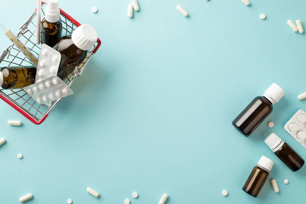 Illness concept. Top view photo of shopping cart with medicines transparent brown bottles pills blisters capsules and thermometer on isolated pastel blue background with copyspace