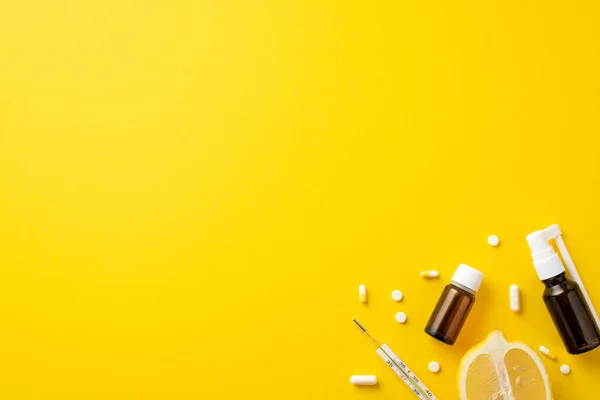 Disease concept. Top view photo of remedy transparent brown bottles pills thermometer and lemon half on isolated yellow background with copyspace