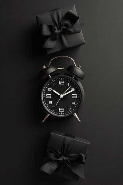 黒い金曜日の販売の概念 トップ表示垂直方向の写真の目覚まし時計とブラックギフトボックスリボン弓で隔離された黒の背景 — ストック写真