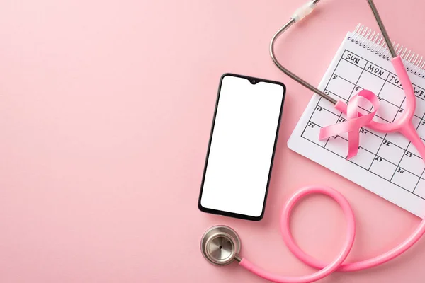 Top view photo of pink ribbon symbol of breast cancer awareness smartphone stethoscope and calendar on isolated pastel pink background with blank space