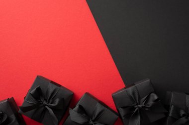 Kara Cuma konsepti. İki renk kırmızı ve siyah arkaplan üzerinde kurdele yayları olan siyah hediye kutularının üst görünümü