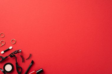 Kara Cuma konsepti. Kozmetik göz fotografı sahte kirpikleri, kirpikleri, kirpikleri kirpikleri, saç fırçaları ve altın halkaları izole edilmiş kırmızı arka planda boş alanlarda.