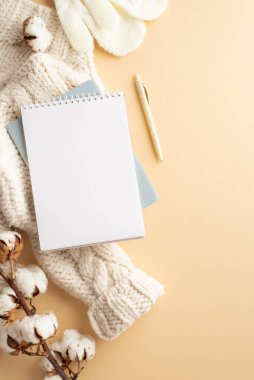 Kış ilham konsepti. Samimi Jumper örgü eldivenlerin dikey üst görünümü not defterleri izole edilmiş bej arkaplan üzerinde kalem ve pamuk dalı boş alan