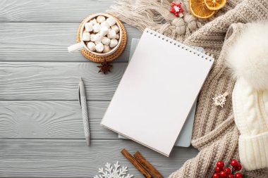 Not defterinin en üstteki fotoğrafı. Kalem boncuk şapka ekoseli sıcak içki bardağı marshmallow ile servis edilen kar tanesi tarçın viburnum ve gri tahta arka planda kurutulmuş portakal dilimleri.