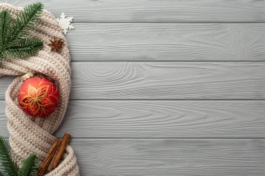 Noel süslemeleri konsepti. Kırmızı mücevherli kar tanesi çam dallarının üst görüntüsü anason örgü ve tarçın çubukları gri ahşap masa zemininde, kopyalanmış