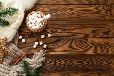 Noel Günü konsepti. Beyaz şapkalı battaniye kabı örülmüş kakao fotoğrafının üst görüntüsü. Üzerinde marshmallow ve rattan servis yapan hasırı hasır yıldız köknar dalları. Ahşap masa arkasında tarçın çubukları ve fotokopi alanı.