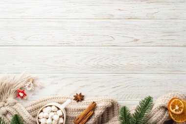 Kış konsepti Çam ağacı dallarının en üst görüntüsü. Bir fincan sıcak çikolata. Kurumuş ekoseli portakal dilimleri, dekoratif tokalar ve beyaz ahşap masa arkasında tarçın çubukları.