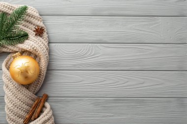 Noel süslemeleri konsepti. Altın sarısı bir çam dalının en üstteki fotoğrafı eşarp örgü anason ve tarçın çubuklar gri ahşap masa zemininde kopyalanmış