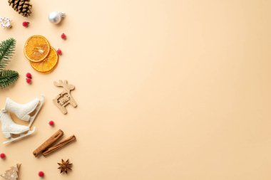 Yeni yıl dekorasyonu konsepti. Mücevherli ahşap geyik buz patenleri, süsleri, kozalaklı tarçın, ökseotu ve kuru portakal dilimleri, izole edilmiş bej arka planda, kopyalanmış bej alanlar.