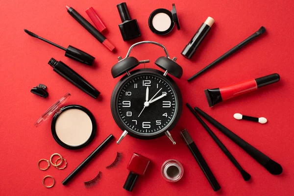 Black friday concept. Top view photo of alarm clock compact powder nail polish mascara false lashes eyeshadow brushes eyebrow gel brow marker lip gloss gold rings barrettes on isolated red background