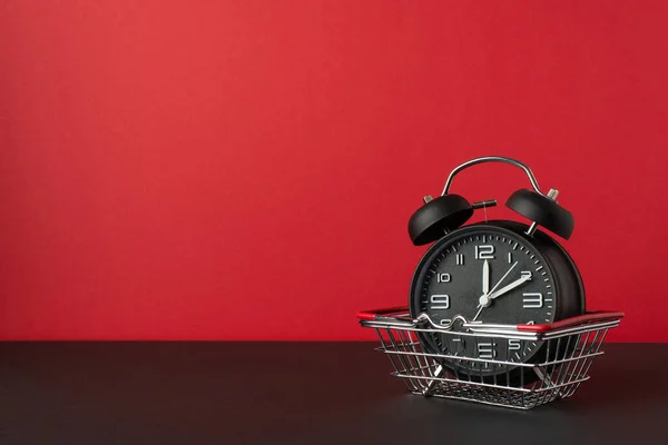 黑色星期五销售概念 黑色桌面红墙背景图上购物车闹钟的照片 — 图库照片