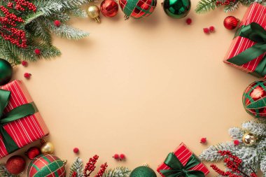 Yeni yıl konsepti. Yeşil kurdeleli kırmızı hediye kutularının en üstteki fotoğrafı. Ökseotu üzümleri ve çam dalları. Karda izole edilmiş bej arka planda.