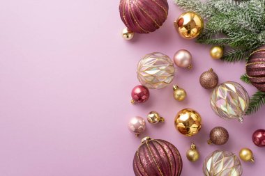 Yeni yıl konsepti. Kardaki çam dallarının üst görüntüsü şeffaf pembe ve izole edilmiş pastel menekşe arkaplanlı altın mücevherler.