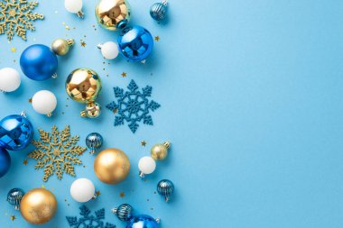 Noel ağacı süslemeleri konsepti. Beyaz mavi ve altın renkli mücevherlerin en üstteki fotoğrafı kar tanesi süslemeleri ve izole edilmiş açık mavi arkaplanda boş alan üzerine parlak konfeti.
