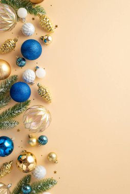 Noel arifesi kavramı. Çam kozalağındaki ladin dallarının dikey üst görüntüsü beyaz şeffaf mavi altın takılar ve izole edilmiş bej arkaplan üzerine konfeti.