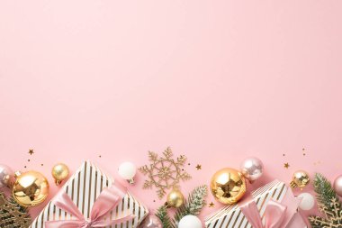 Yeni yıl konsepti. Üstünde kurdele dalları olan büyük hediye kutularının en üstteki fotoğrafı donuk altın sarısı çam dalları kar taneleri süsü ve tenha açık pembe arka planda boş alan konfetisi.