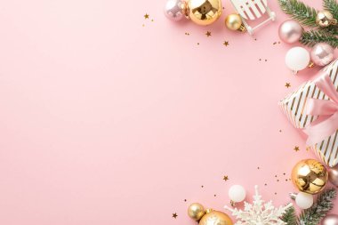 Noel arifesi kavramı. Kurdeleli hediye kutusunun en üstteki fotoğrafı çam ağacından dallarla altın sarısı, beyaz, altın sarısı, kar tanesi kızağı süslemeleri ve kopyalanmış açık pembe arka planda bulunan konfetiler.