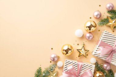 Yeni yıl atmosferi konsepti. Kurdeleli mevcut kutuların üst görüntüsü altın ve pembe takılar yıldız süslemeleri kardaki köknar dalları ve izole edilmiş açık bej arka plandaki boş alan konfetileri