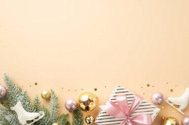 Yeni yıl konsepti. Hediye kutusu altının ve pembe mücevherlerin en üstteki fotoğrafı buz patenleri kardaki çam dalı süslemeleri ve izole edilmiş açık bej arka planda parlayan konfeti boş alan