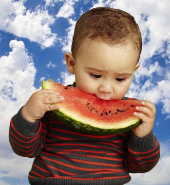 Çocuk bir gökyüzü arka plan karpuz dilimi tatma