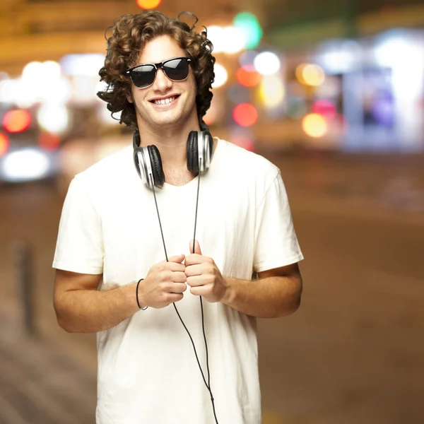 年轻男子戴着耳机在城市夜间肖像 — 图库照片