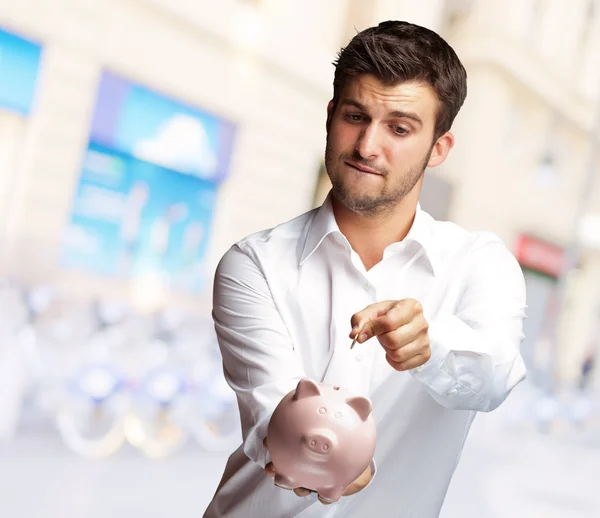 En affärsman som lägger ett mynt i en spargris rosa — Stockfoto