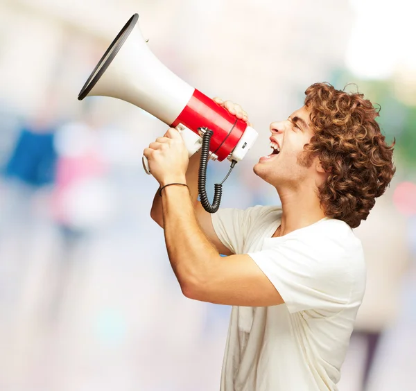 Porträt eines jungen Mannes, der mit einem Megafon schreit — Stockfoto