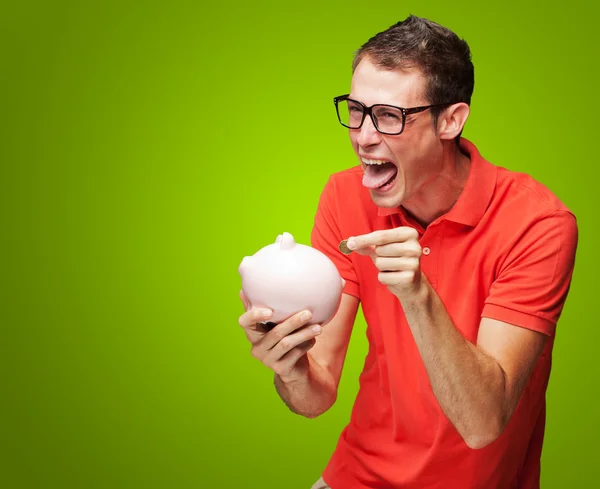 Retrato del hombre con alcancía insertando una moneda — Foto de Stock