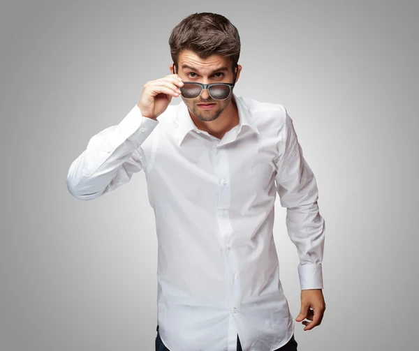 Retrato de hombre joven dando mirada mientras sostiene gafas — Foto de Stock